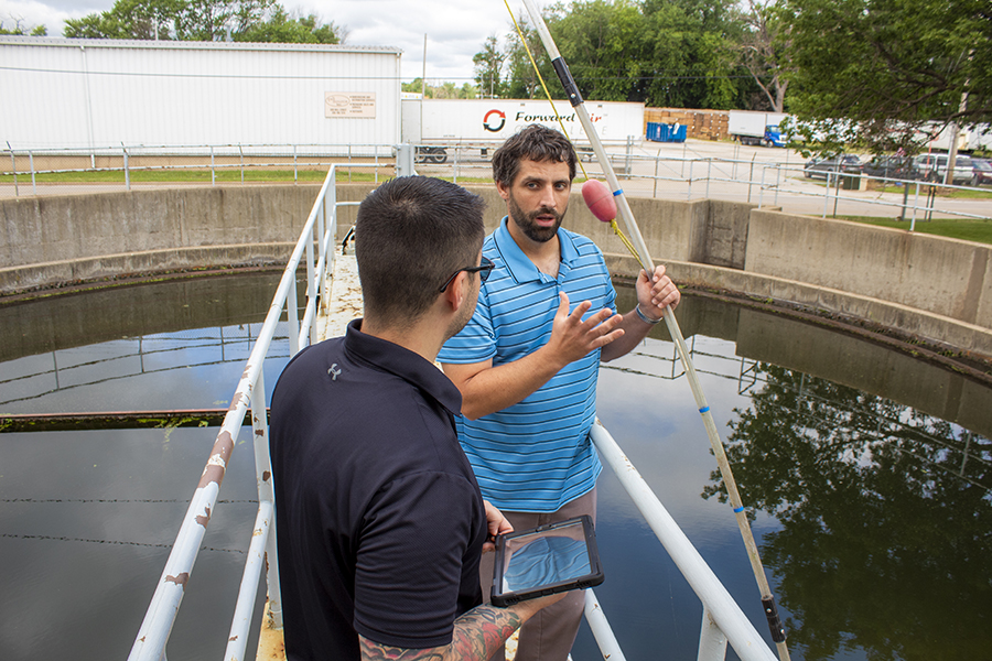 Two men overlooking a wastewater treatment pool and talking