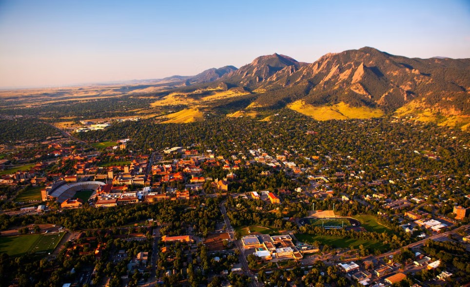 Overview photo of Boulder, Colorado + town sprawl with Rocky Mountains in background