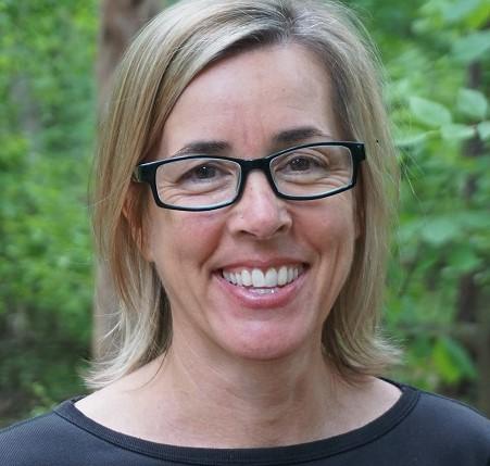 Dana Haine - smiling woman with blonde shoulder length hair, black rectangular glasses, and a black shirt