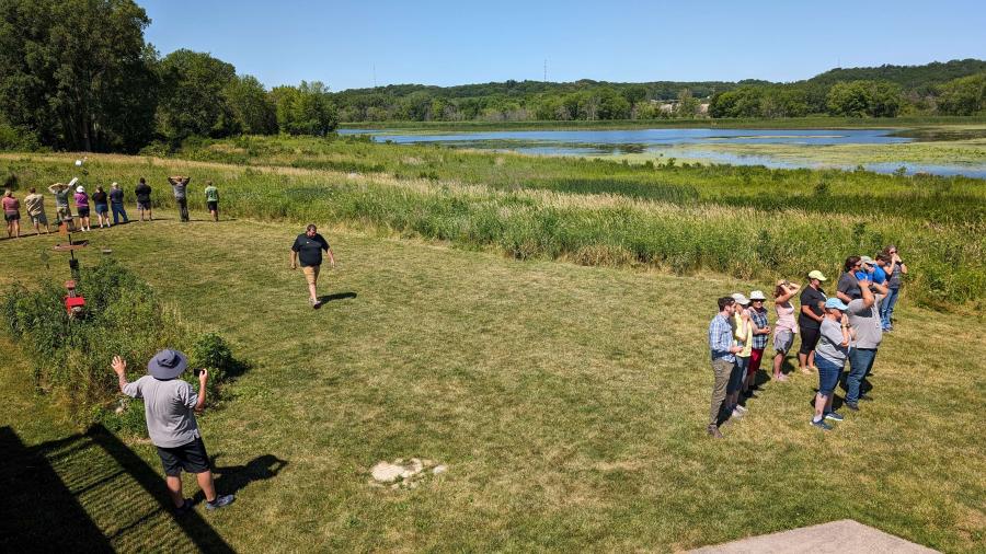 Two groups of adults on opposite ends of a field with one adult in the middle of the groups