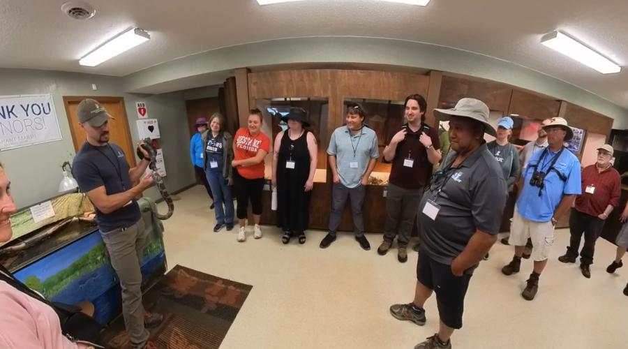 Several educators standing around a speaker holding a snake.